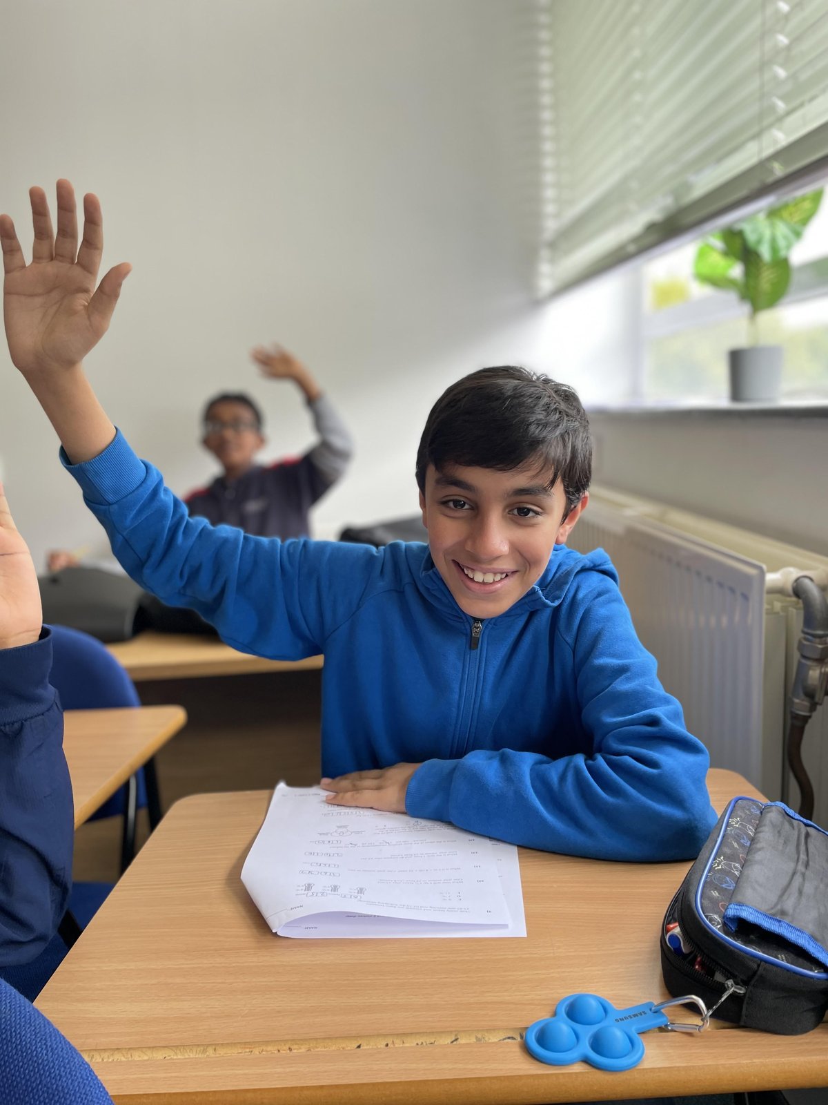 A happy Bright Mentors student raising his hand during a tuition class